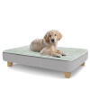 Een puppy rustend op het grote Topology puppybed met vierkante houten poten