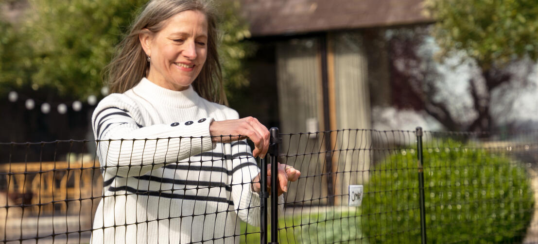 Vrouw die kippengaasdeur opent