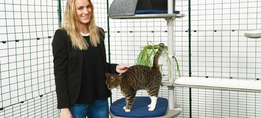 Meisje dat haar kat aait die op de Freestyle buitenkattenboom speelt