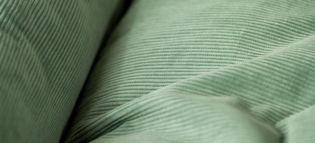 Close-up van ribfluweelstructuur op ribfluweel mosnest hondenbed.