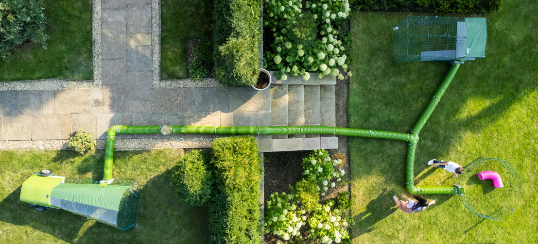 Drone-opname van Zippi ren, box en tunnelsysteem opgesteld in een tuin.