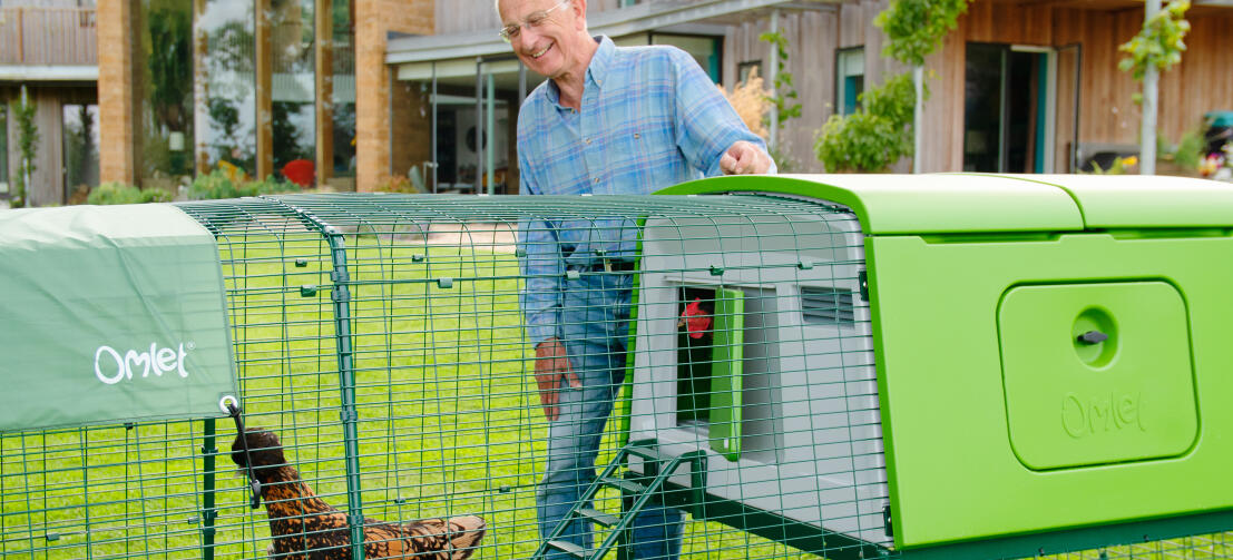 Man met groot Eglu kippenhok en ren in een tuin Man met groot Eglu kippenhok en ren in een tuin