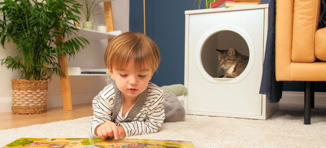 Schattige kat in Omlet Maya kattenhuis met kind dat vooraan een boek leest