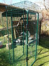 Een inloopren in een tuin met veel houten accessoires erin