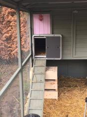 Een Autodoor die vastzit aan een groot houten kippenhok met een oprit naar de deur