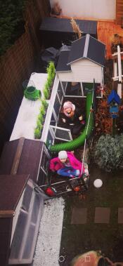 Twee meisjes zaten in een tuin met een Zippi tunnel opgezet met een konijnenhok
