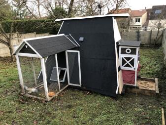 Omlet grijze automatische kippenhokdeur bevestigd aan houten kippenhok