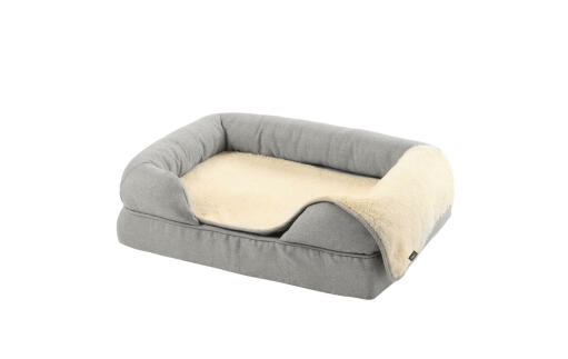 Een grijs traagschuim bolster bed maat small 24 met een pluche deken erop