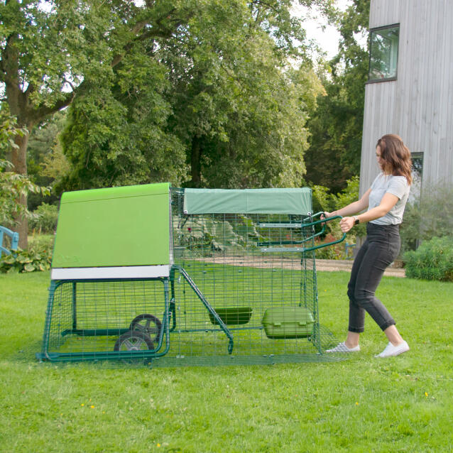 Een vrouw die een Eglu Go kippenhok verplaatst