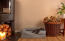 Een kleine zwarte hond liggend op een grijs traagschuim bolsterbed in een woonkamer