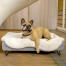 Hond liggend op Omlet Topology hondenbed met schapenvacht topper en ronde houten voetjes