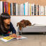 Hond zittend op Omlet Topology hondenbed met gewatteerde topper en zwarte rail voetjes die meisjesboek onderzoeken