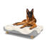 Hond zittend op een groot Topology hondenbed met schapenvacht topper en houten ronde poten