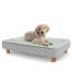Een puppy rustend op het grote Topology puppybed met ronde houten poten