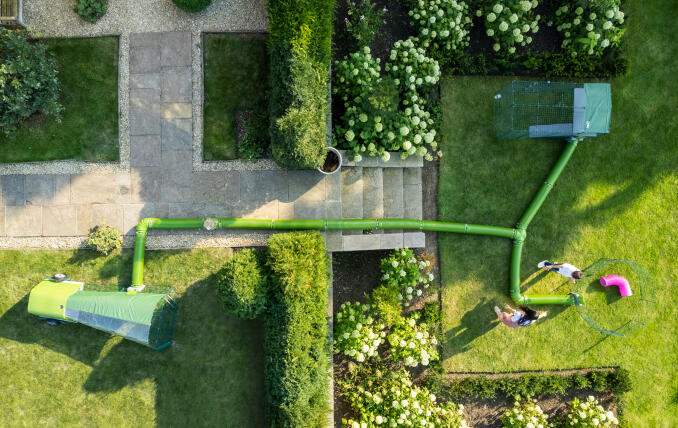 Drone-opname van Zippi ren, box en tunnelsysteem opgesteld in een tuin.