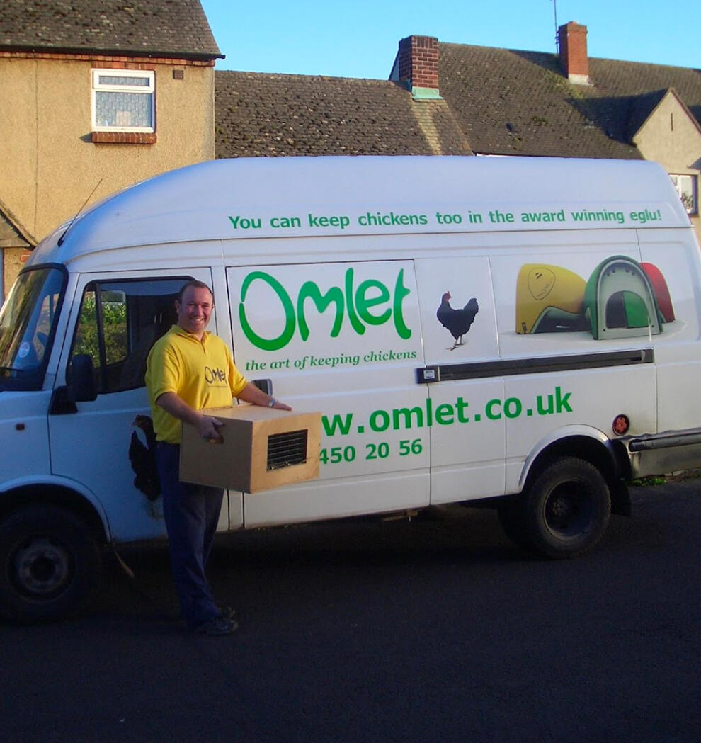 Een bezorger naast een bestelbus van het merk Omlet met een doos kippen