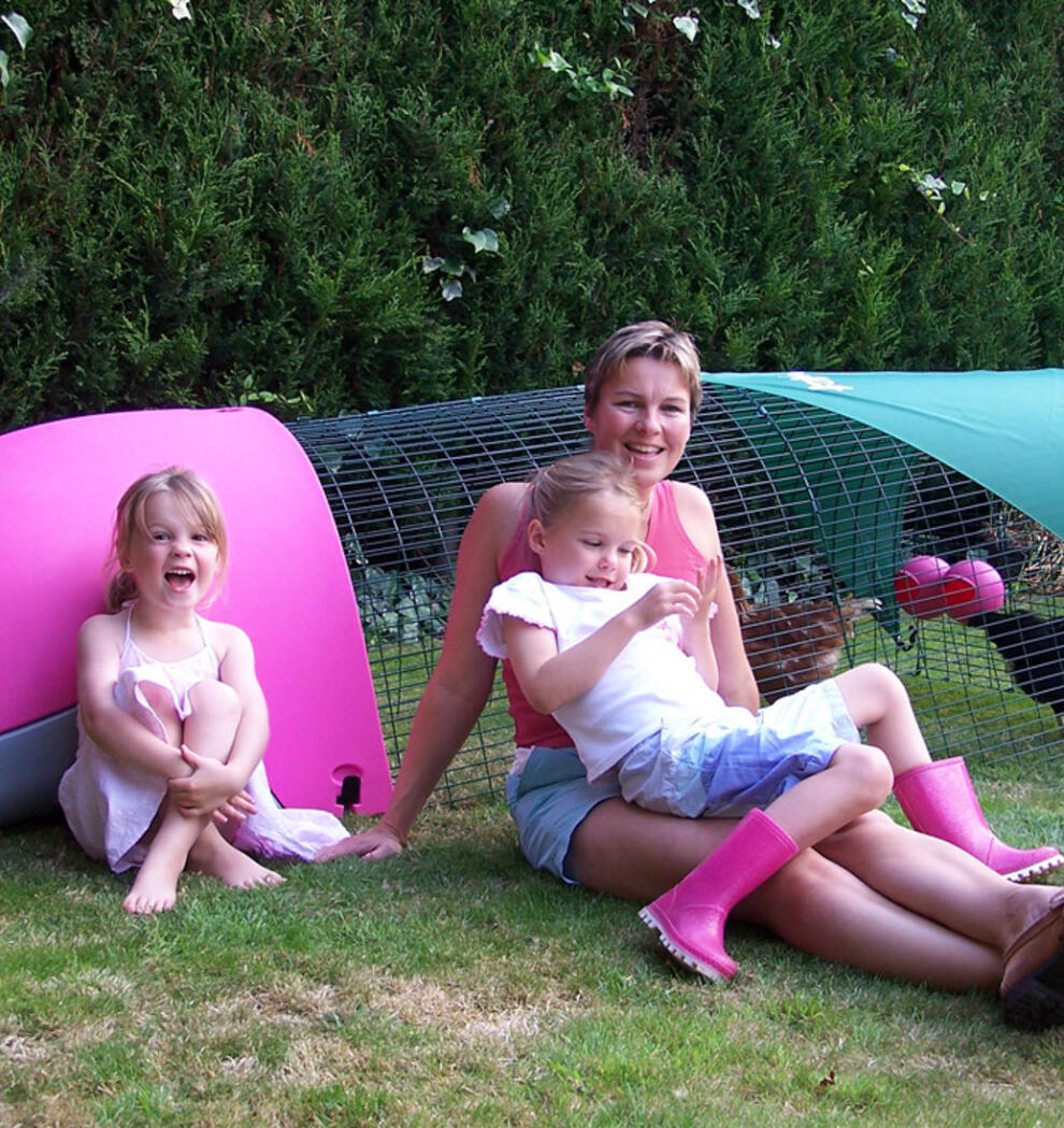 Een gezin naast een roze Eglu kippenhok