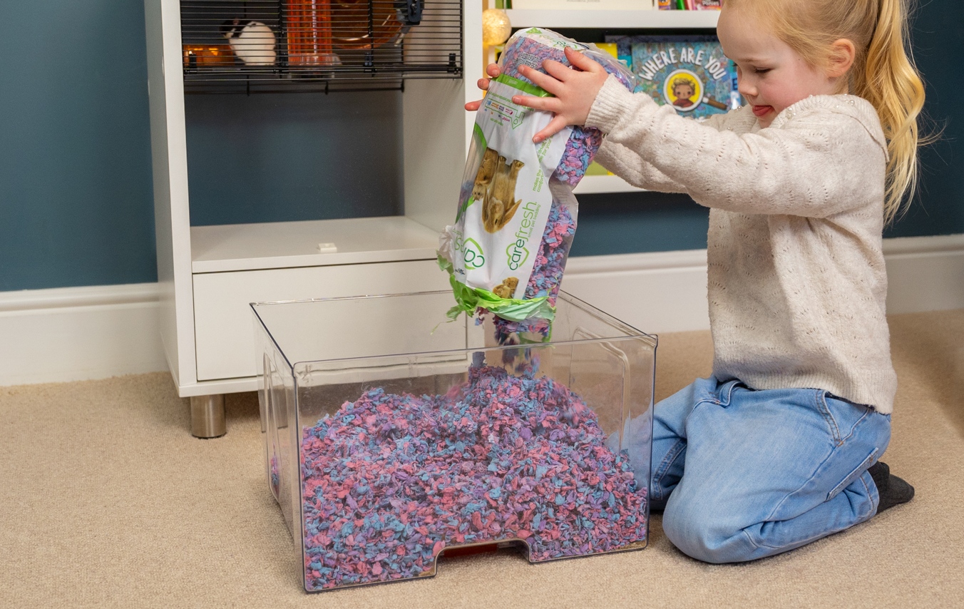 kind maakt de nestlade van een Qute hamsterkooi schoon