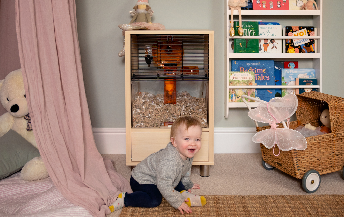 Kleuter speelt in een slaapkamer met een hamsterkooi op de achtergrond