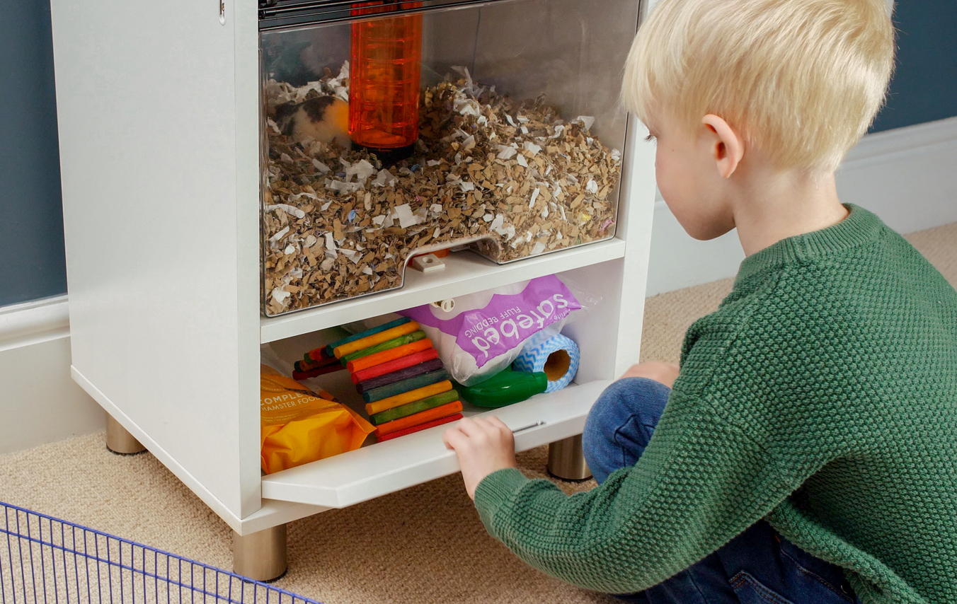 Kind bergt nestmateriaal voor hamsters op in het opbergvak van de Qute hamsterkooi