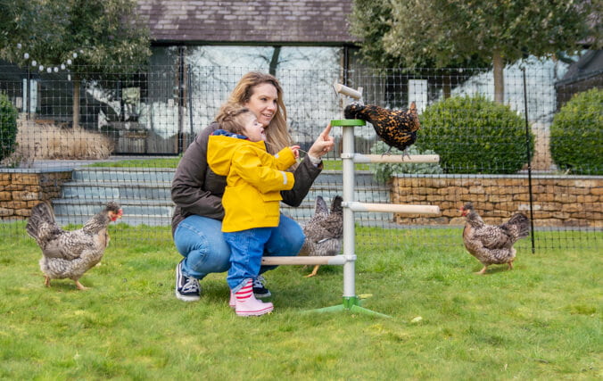 moeder en dochter in hun tuin spelend met hun kippen