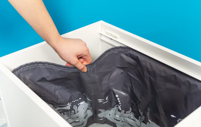 A grey plastic liner in a litter tray being pulled off