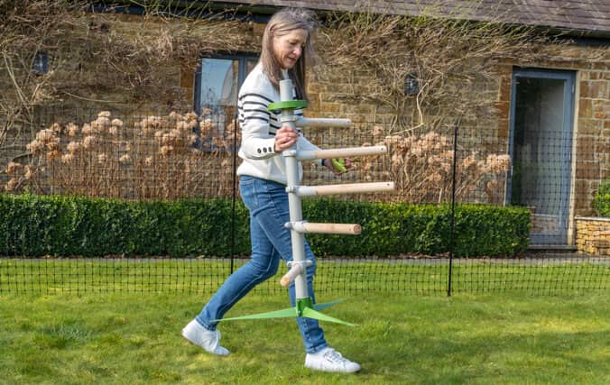 Vrouw verplaatst moeiteloos de vrijstaande zitstok voor kippen